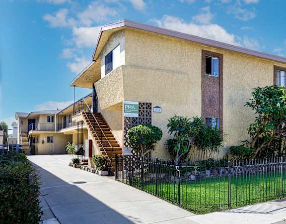 a yellow house with a yard and a fence in front of it