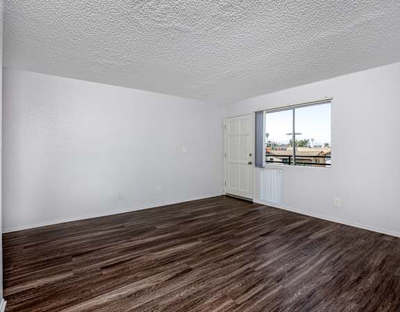 Empty room with wooden flooring and a window.