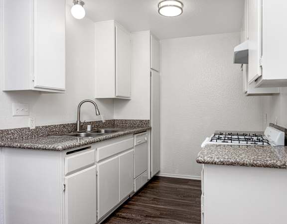 A kitchen with white cabinets and a granite countertop.