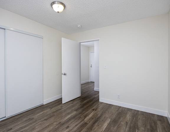 an empty bedroom with white walls and wood flooring