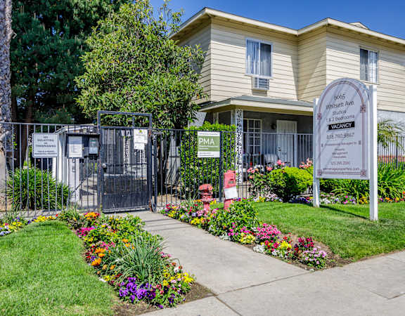 a home with a sign and flowers in front of it