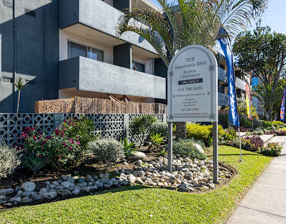 a sign in front of a building with palm trees