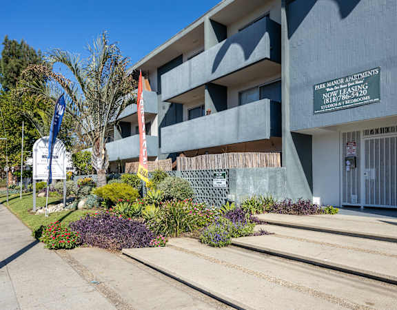 the front of a building with stairs and plants in front of it