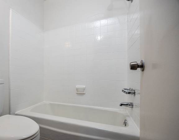 a white bathroom with a tub and a toilet
