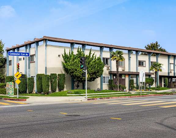 a large building with palm trees in front of it on a street