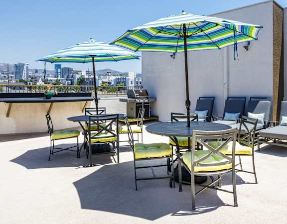 a patio with tables and chairs and umbrellas on the roof of a building