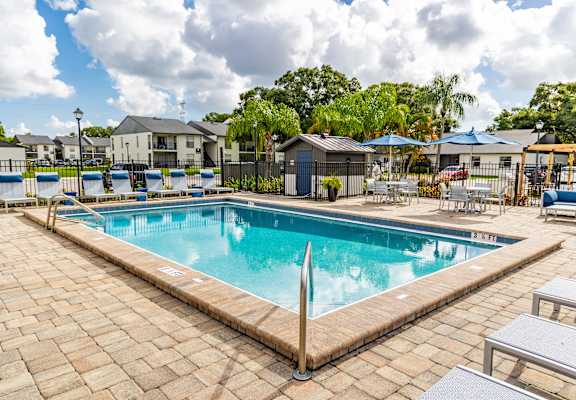 A large outdoor swimming pool surrounded by a brick patio.