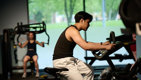A man is working out on a rowing machine in a gym.