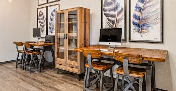 A wooden desk with a computer and a cabinet in front of a wall with framed pictures.