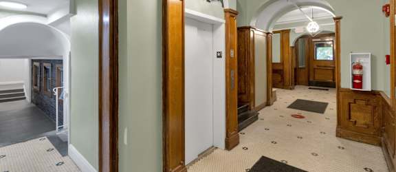 A hallway with a white tiled floor and a mix of wood and painted walls.