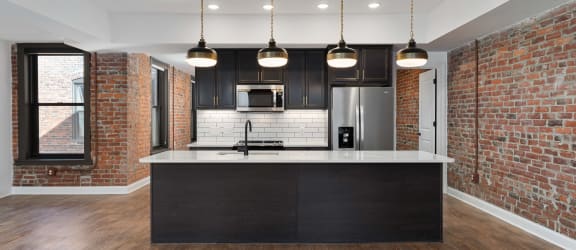 a kitchen with a large island and a brick wall at The Madison, Columbus