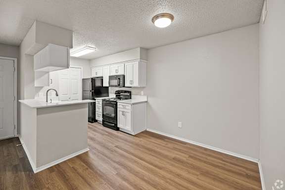 A kitchen with white cabinets and black appliances. at Highland Park, Texas, 76132