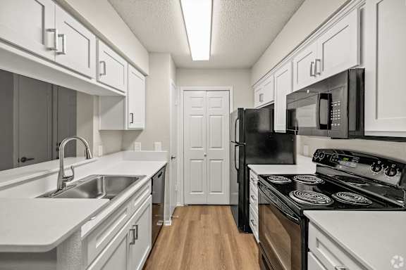 A kitchen with white cabinets and black appliances. at Highland Park, Texas, 76132