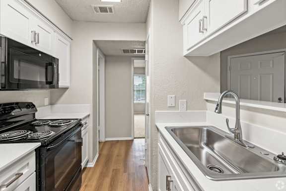 A kitchen with a stove, sink, and cabinets. at Highland Park, Texas, 76132