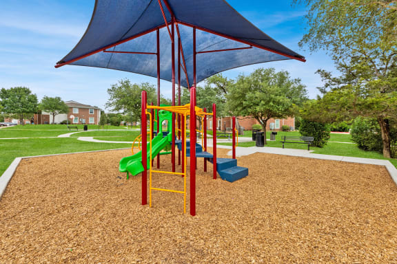 a playground with a swing set and other playground equipment in a park at Sandy Creek Apartments, Bryan, Texas