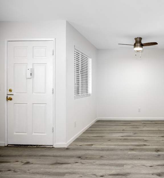 an empty room with white walls and wood floors and a window