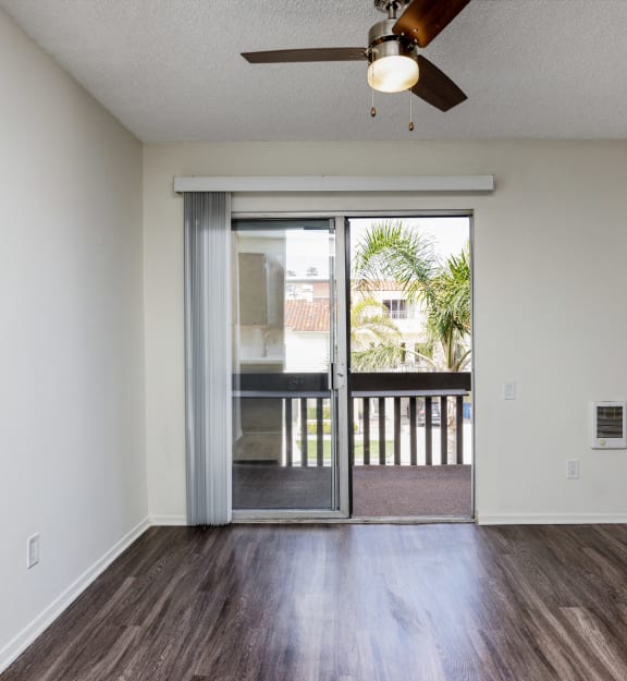 an empty living room with a sliding glass door to a balcony