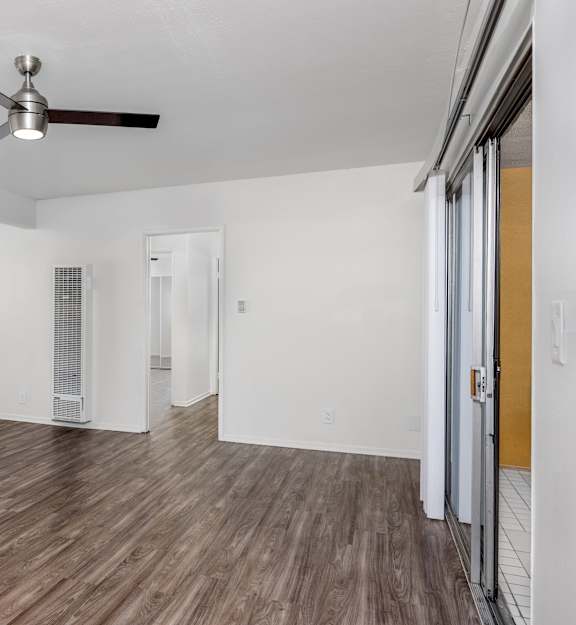 A room with a ceiling fan and wooden flooring.