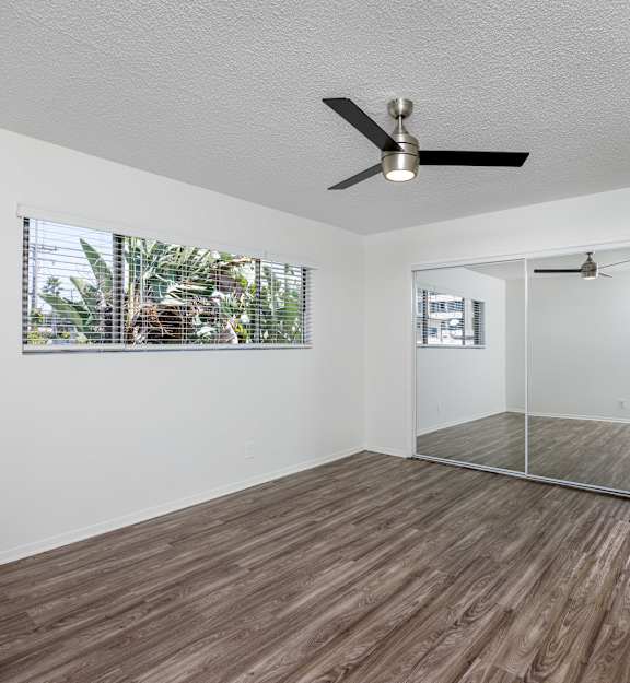 A room with a ceiling fan and wooden flooring.