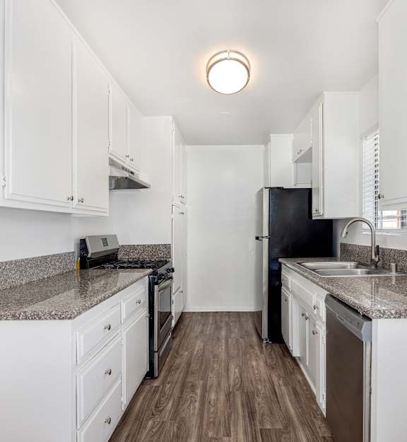 A kitchen with white cabinets and a granite countertop.