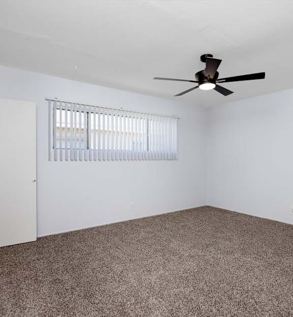 A room with a ceiling fan and a window with blinds.