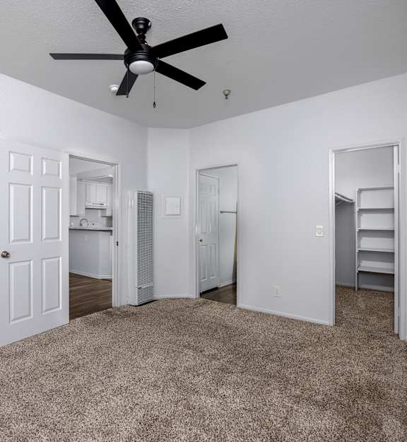 A room with a ceiling fan and carpeted floor.