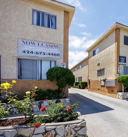 A street view of a Now Leasing sign in front of a building.