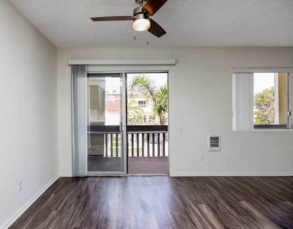 an empty living room with a sliding glass door to a balcony