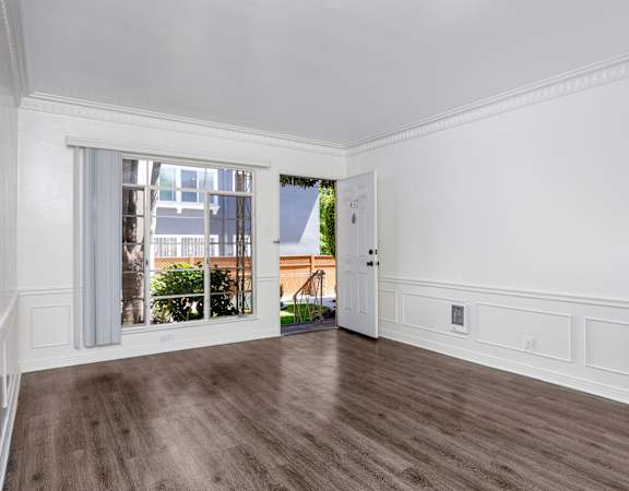 an empty living room with a large window and wood floors