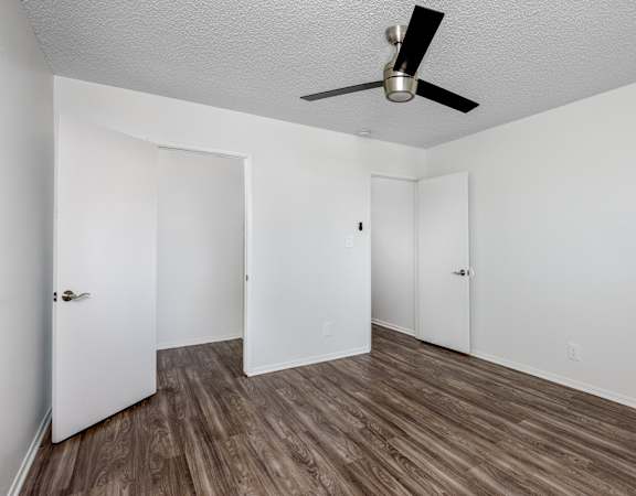 A room with a ceiling fan and wood flooring.