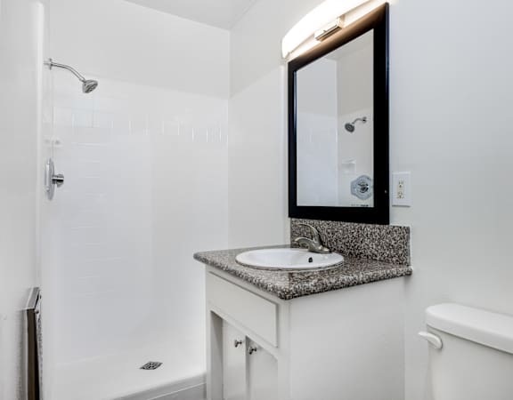 A white bathroom with a sink, mirror, and toilet.