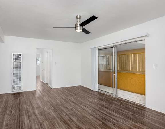 A room with a ceiling fan and sliding glass doors.