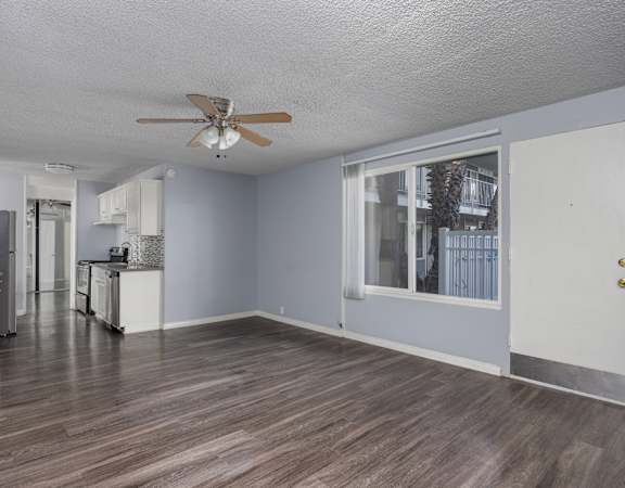 A room with a ceiling fan and wooden flooring.