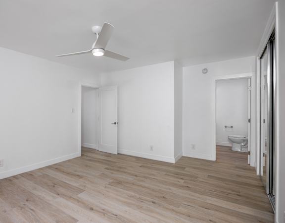 A room with a ceiling fan and wooden flooring.
