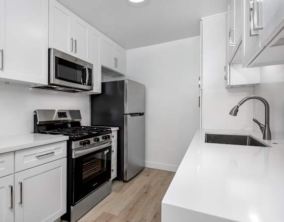 A kitchen with white cabinets and black appliances.