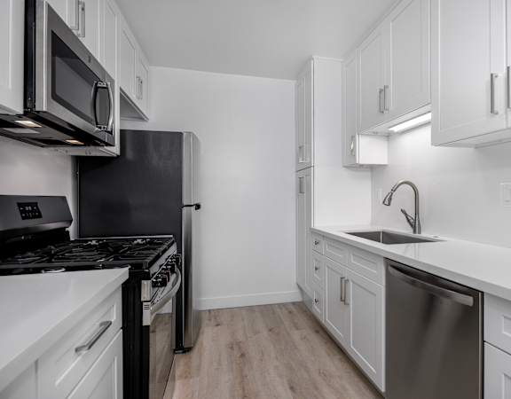 A modern kitchen with white cabinets and stainless steel appliances.