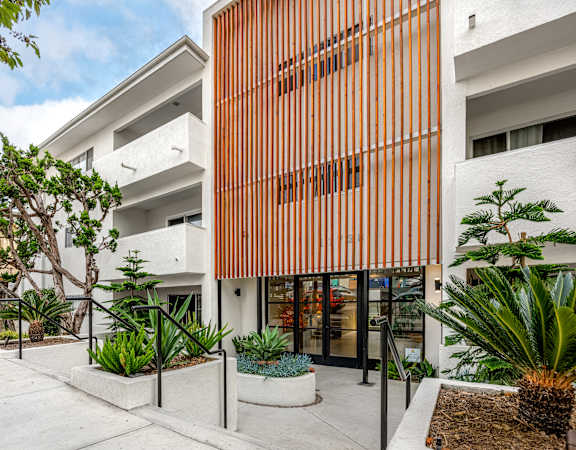 A modern building with a white and orange facade and a landscaped courtyard.