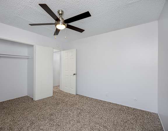 A room with a ceiling fan and carpeted floor.