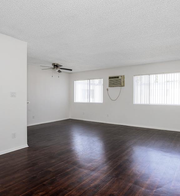 an empty living room with hard wood floors and a ceiling fan