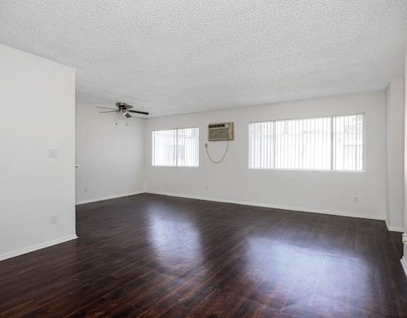 an empty living room with hard wood floors and a ceiling fan