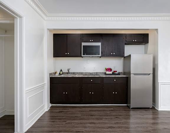 a kitchen with dark cabinets and a stainless steel refrigerator