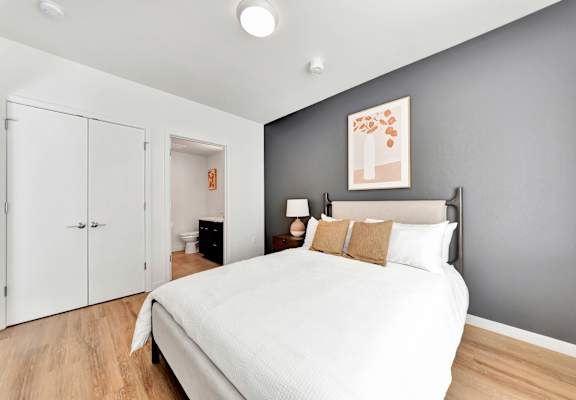 A bedroom with a large bed and a painting on the wall.