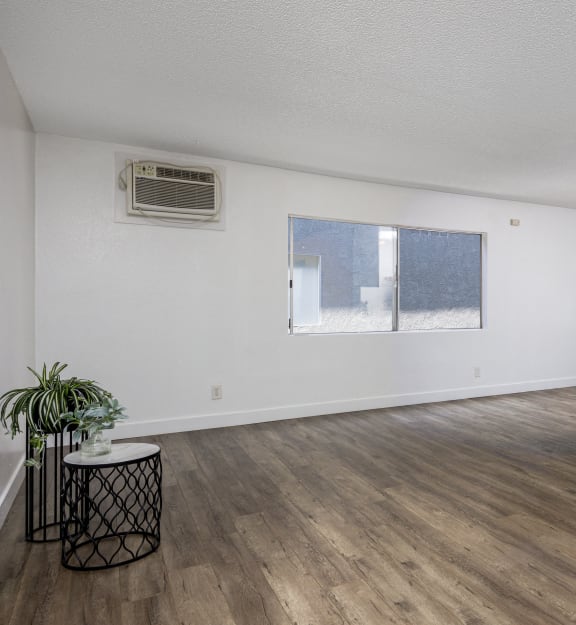 the living room and dining room of an apartment with white walls and wood floors