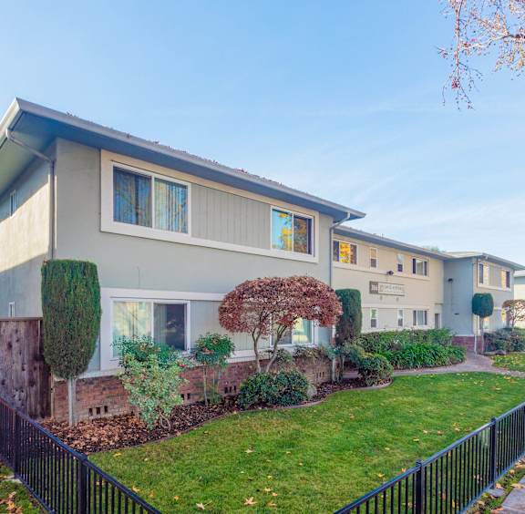 A row of houses with a black fence in front.