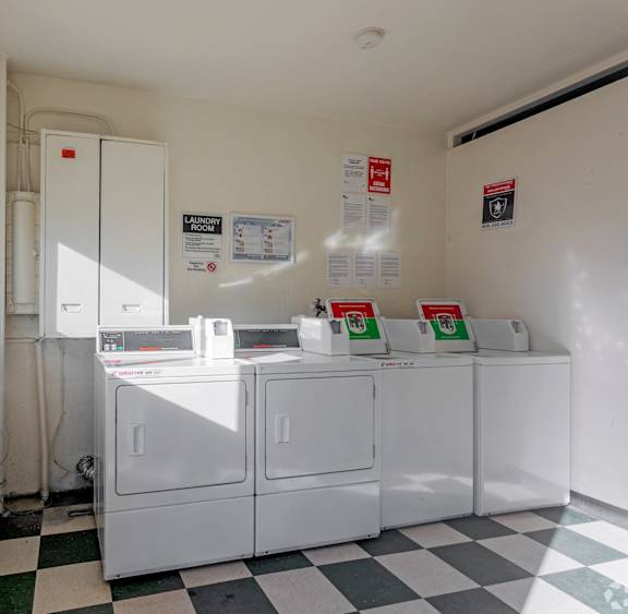 A laundromat with washers and dryers and a black and white checkered floor.