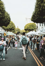 people walking down the street at a farmers market