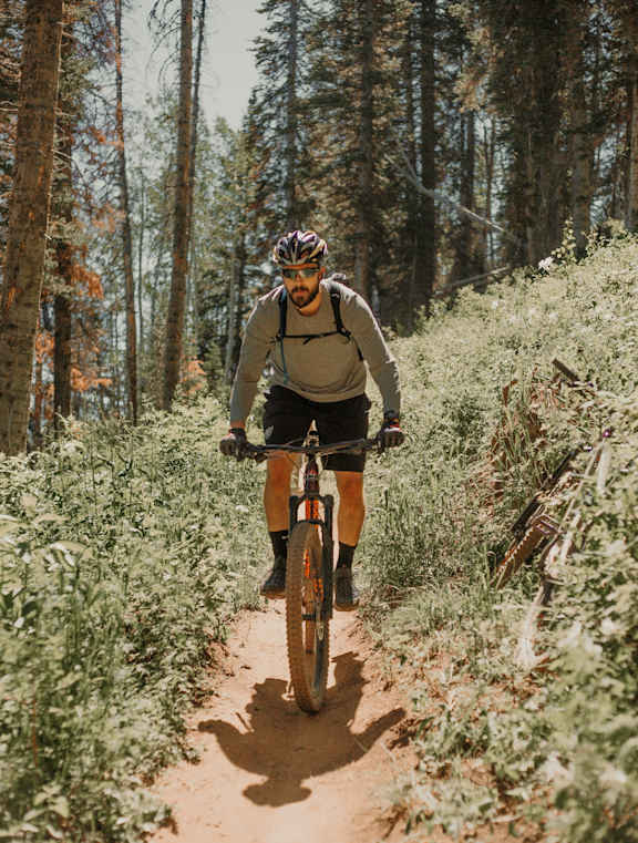 A man riding a bicycle on a dirt trail in the woods.