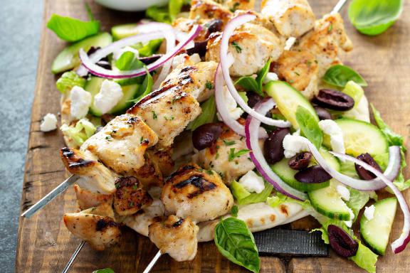 a wooden cutting board with chicken salad and dressing