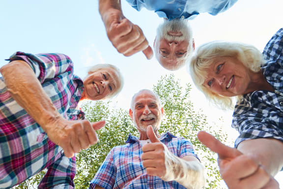 a group of seniors standing in a circle and giving thumbs up