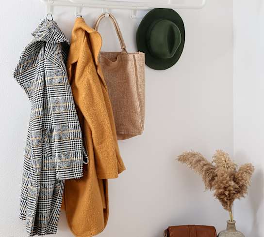 a white shelf with clothes and a hat hanging on it